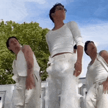 a group of men in white clothes are dancing in front of a blue sky .