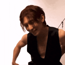 a man wearing a black vest is smiling and looking down at something