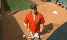 a man in a red jersey is standing on a baseball field holding a bat .