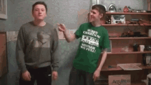 two men are standing next to each other in a room and one of them is wearing a merry christmas shirt