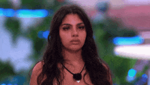 a woman with long hair is standing in front of a blurry background and looking at the camera .