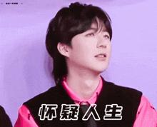 a young man wearing a pink shirt and a black vest with chinese characters on it .