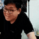 a man wearing glasses and a black shirt is making a funny face in a room .