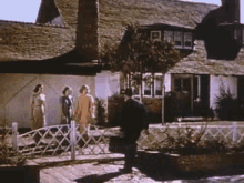 a group of people are walking across a wooden bridge in front of a house .