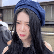 a woman wearing a blue hat has a necklace that says ' l ' on it