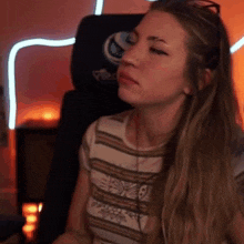 a woman is sitting in a gaming chair wearing headphones and a striped shirt .