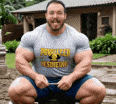 a man wearing a shirt that says powlleed resineund is squatting down