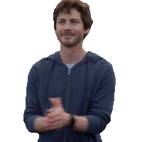 a man in a blue hoodie applauds with his hands together