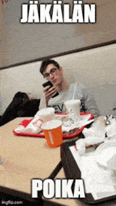 a man sits at a table in a restaurant looking at his phone with a caption that says poika