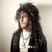 a man wearing a black wig with the word mcdh on the bottom left