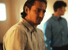 a man in a white shirt is standing in front of two other men in blue shirts