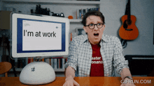 a man sitting at a desk with a computer monitor that says " i 'm at work "