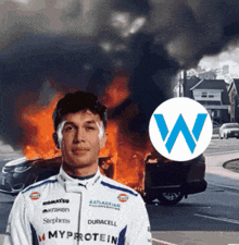 a man stands in front of a burning car and a sign that says myprotein