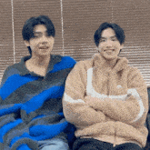 two young men are sitting next to each other on a couch .