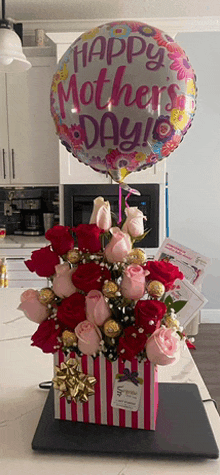 a balloon that says happy mother 's day sits above a bouquet of roses