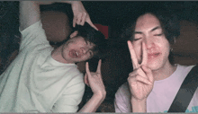 two young men are making funny faces and giving peace signs