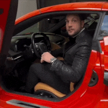 a man in a suit is sitting in a red car