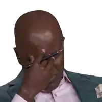 a man wearing a suit and a pink shirt looks down with his eyes closed