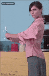a woman in a pink shirt is holding a large knife in her hand .