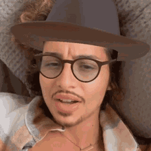 a man wearing glasses and a hat is making a face