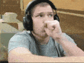 a man wearing headphones and a grey shirt is making a funny face