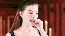 a woman is eating something with her tongue out in a room .