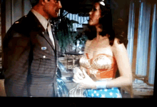 a man in a suit and tie stands next to a woman in a wonder woman outfit