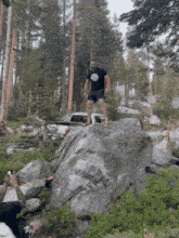 a man standing on a large rock in the woods