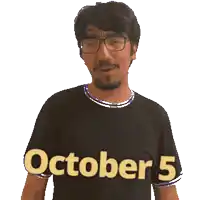 a man wearing glasses and a black shirt with the words october 5 on it