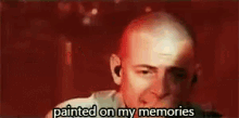 a man with a bald head is holding a microphone in his hand and says `` painted on my memories '' .