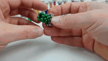 a close up of a person holding a green bead in their hand