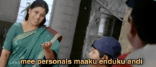 a woman in a green sari is standing next to a boy in a blue hat and talking to him .