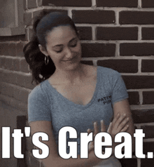 a woman standing in front of a brick wall with the words " it 's great " above her