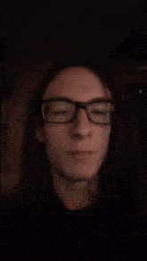 a young man with long hair wearing glasses is making a funny face
