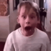 a young boy is making a surprised face while wearing a hat and a white shirt .