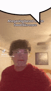 a man wearing glasses and a red shirt is standing in a room and talking about food .