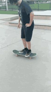 a man in a black shirt is riding a skateboard on a concrete surface