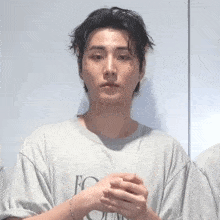 a young man wearing a grey t-shirt with the letter e on it