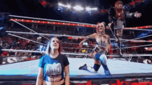 a woman in a blue shirt is kneeling down in a wrestling ring ..