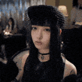a woman with long black hair wearing a black hat and choker