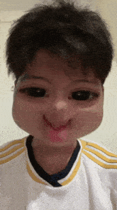a young boy wearing a white shirt with yellow stripes makes a funny face