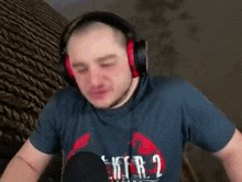 a man wearing headphones and a blue shirt is standing in front of a microphone and making a funny face .