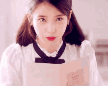 a woman in a white dress is holding a card that says " i love you "