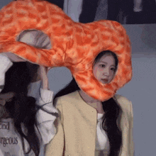 a woman wearing a giraffe hat is holding a stuffed animal on her head .