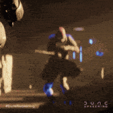 a poster for dune awakening shows a man holding a knife