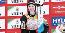 a woman in a gorenje hat holds a trophy in front of a wall of advertisements
