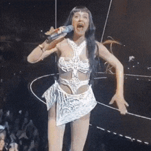 a woman in a white dress is singing into a microphone on stage .
