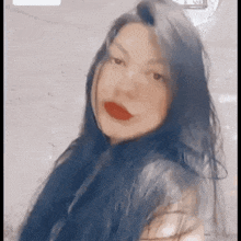 a woman with long black hair and red lipstick looks at the camera .
