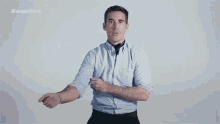 a man in a light blue shirt and black tie is standing in front of an esquire ad