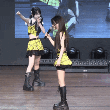 a girl in a yellow plaid top is holding a microphone